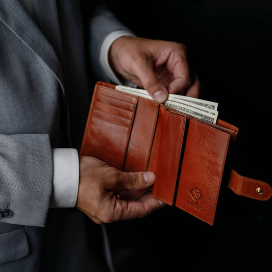 Elegant brown leather wallet held open with cash inside, showcasing style and quality.